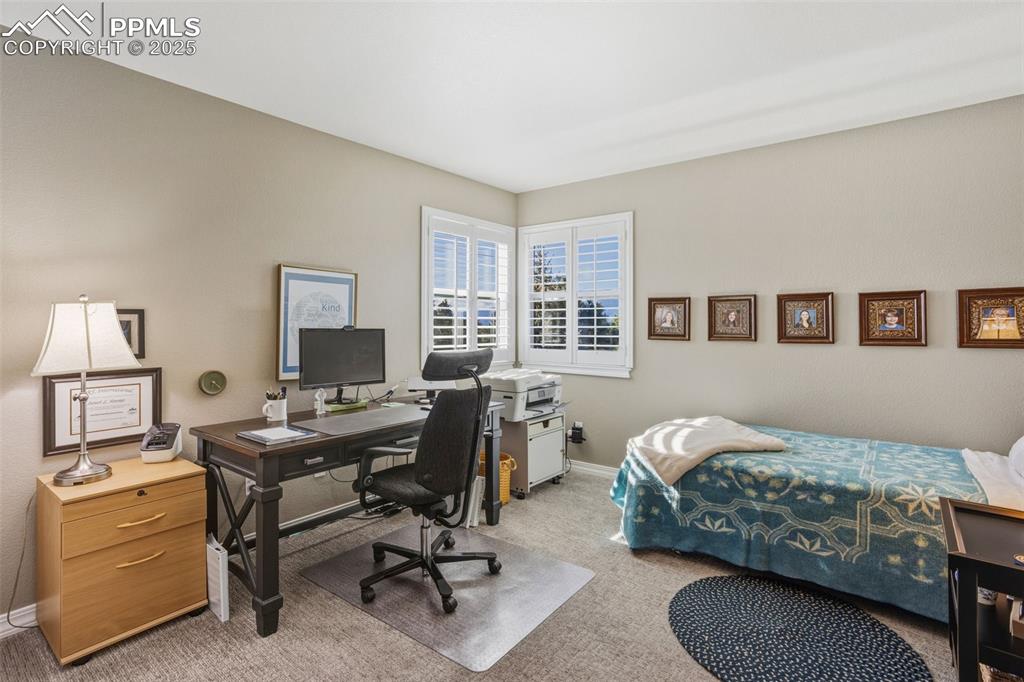 Carpeted bedroom featuring an office area and baseboards