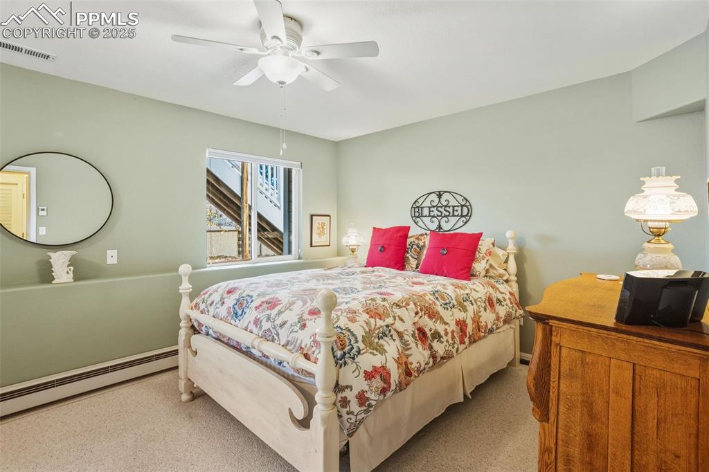 Bedroom featuring a baseboard heating unit, carpet floors, and a ceiling fan