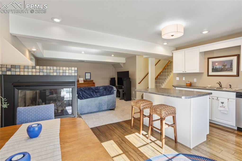 Kitchen with a kitchen bar, open floor plan, white cabinetry, a kitchen island, and recessed lighting