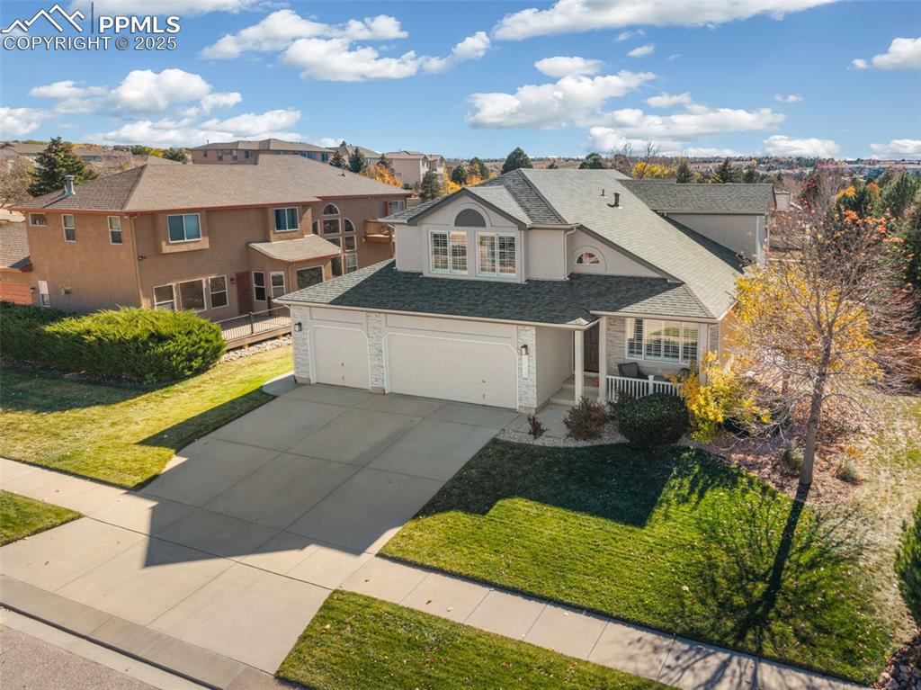 Traditional-style home with stone siding, concrete driveway, a front yard, and covered porch