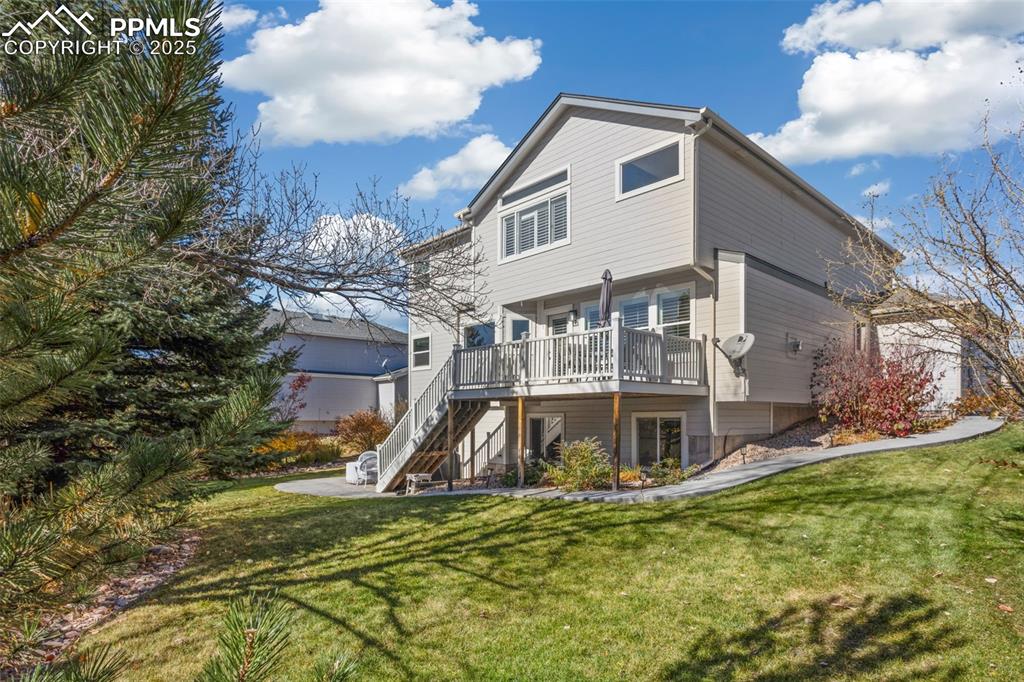 Rear view of house featuring a deck, a yard, and stairway