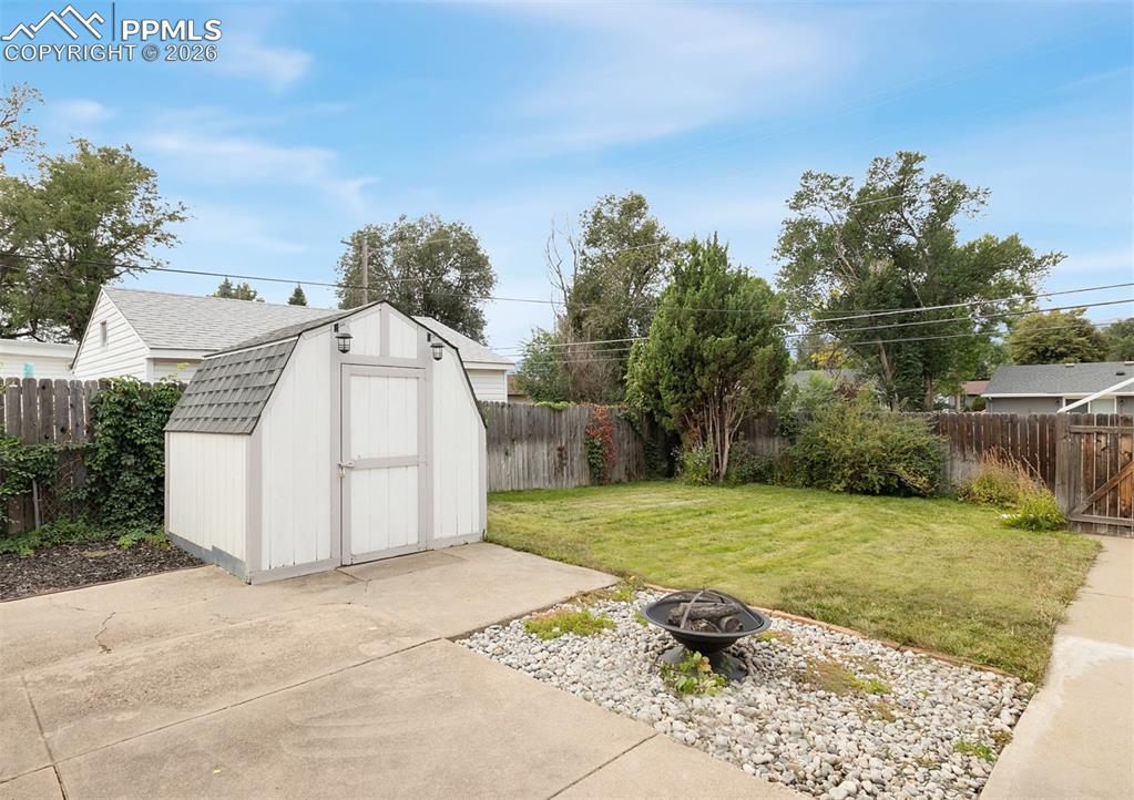 Inviting back yard with large covered patio, firepit, lawn, cute shed, and very large 2-1/2 car garage.