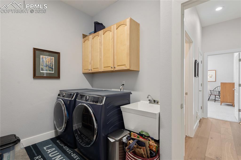 Main level laundry room has cabinets, sink, and door to garage
