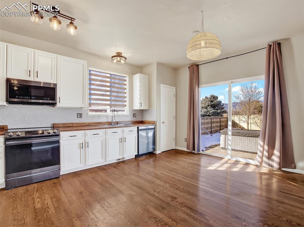 Open kitchen, eat-in dining area with updated appliances and walk out sliding door to patio/hot tub