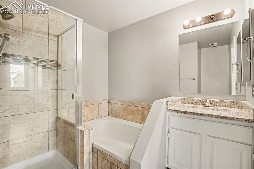 Full bathroom featuring a bath, vanity, and a shower stall