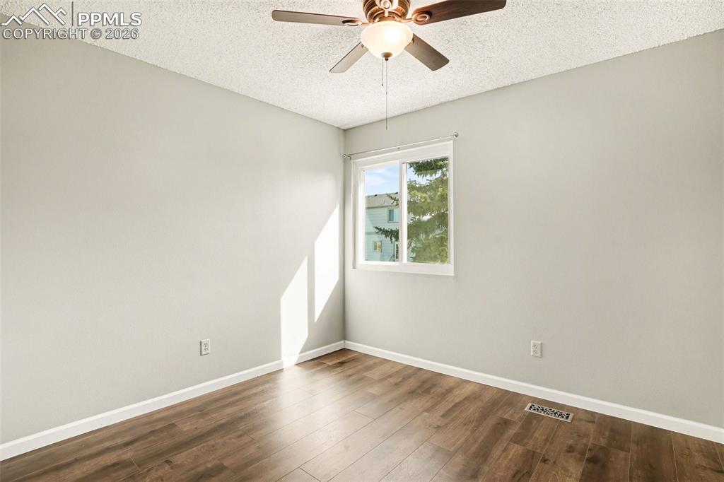 Spare room with dark wood-style floors, a textured ceiling, and ceiling fan