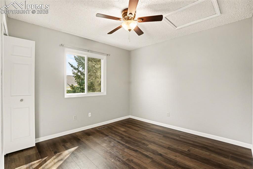 Unfurnished bedroom featuring dark wood-style floors, a ceiling fan, and a textured ceiling