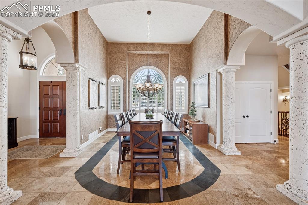 Dining room featuring a chandelier, plenty of natural light, arched walkways, and a towering ceiling