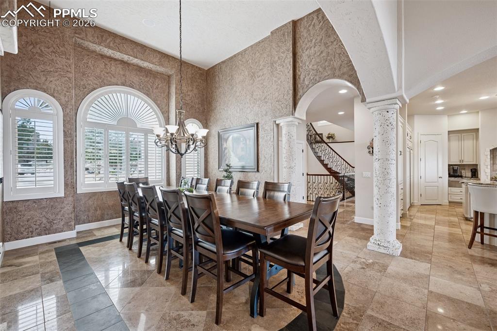 Dining area with arched walkways, decorative columns, baseboards, a towering ceiling, and recessed lighting