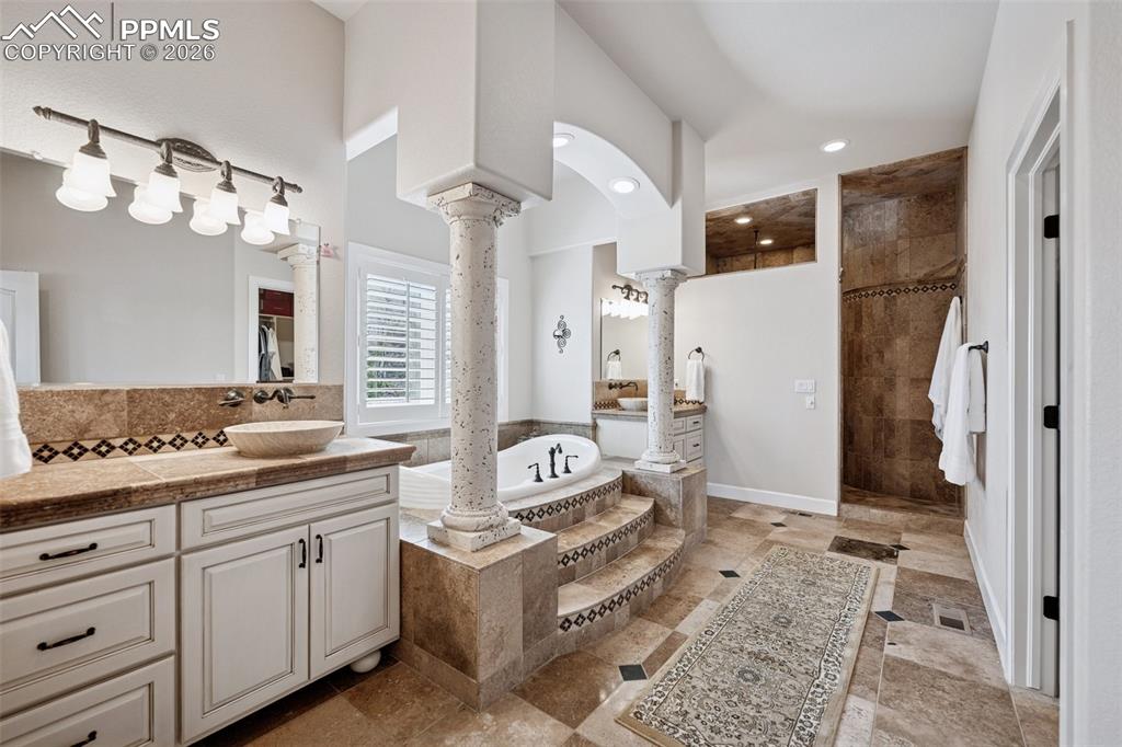 Bathroom with recessed lighting, ornate columns, vanity, a walk in shower, and a garden tub