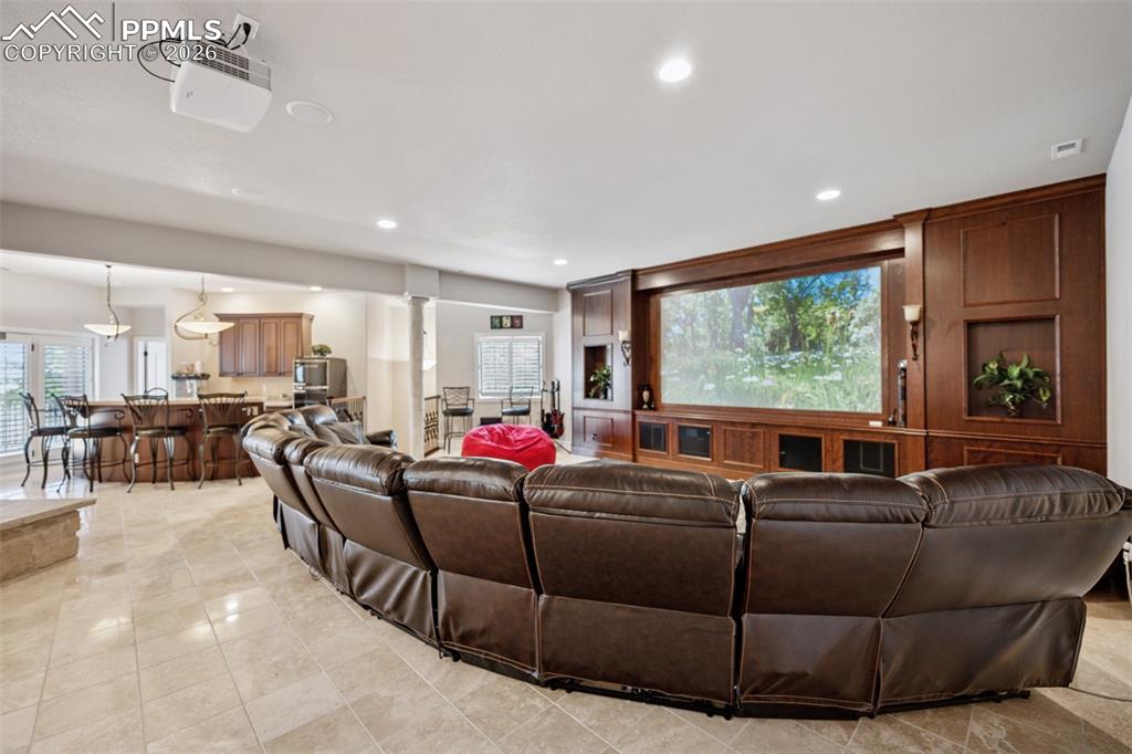 Living room with recessed lighting, visible vents, light tile patterned floors, and decorative columns