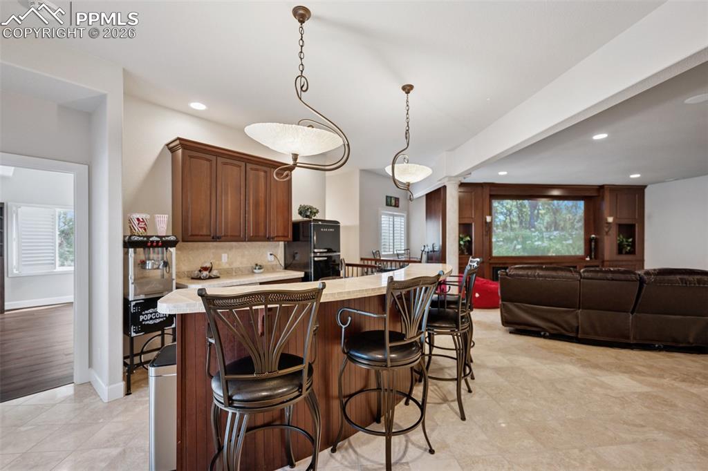 Kitchen featuring a breakfast bar area, recessed lighting, tasteful backsplash, and light countertops