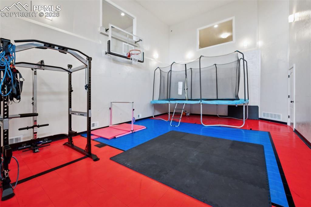 Exercise room featuring a towering ceiling and visible vents