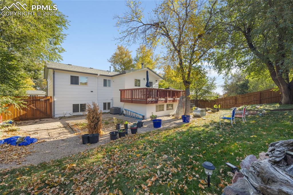 Rear view of property with a fenced backyard, a wooden deck, and a patio area