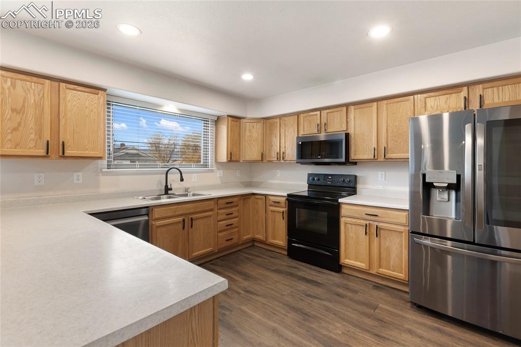 Kitchen with appliances with stainless steel finishes, light countertops, dark wood-type flooring, and recessed lighting