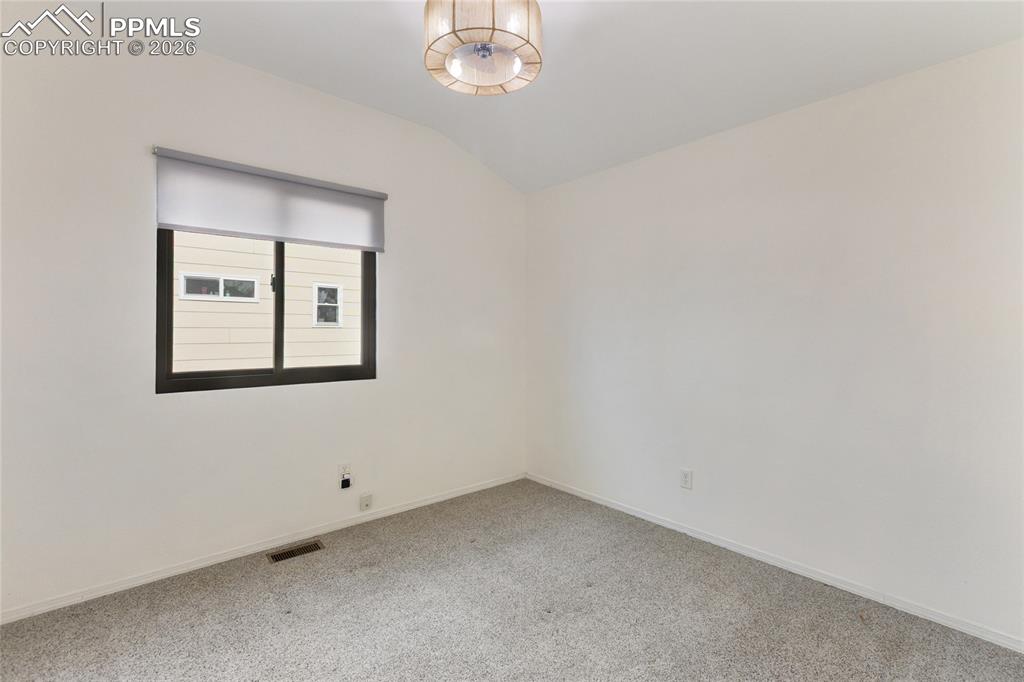 Empty room with lofted ceiling and carpet floors