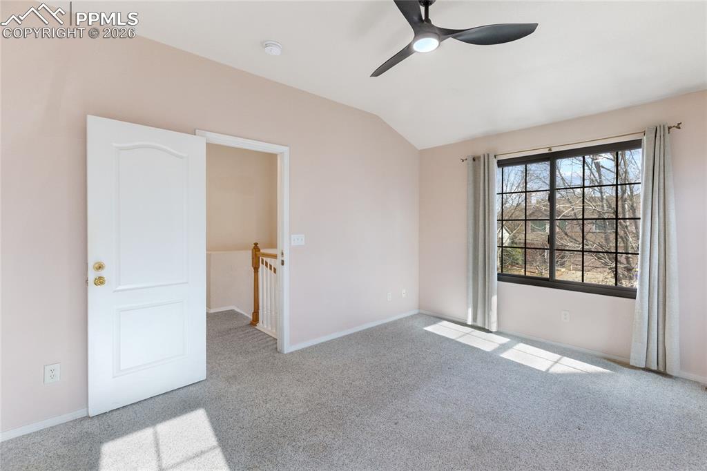 Unfurnished room with light colored carpet, vaulted ceiling, and ceiling fan