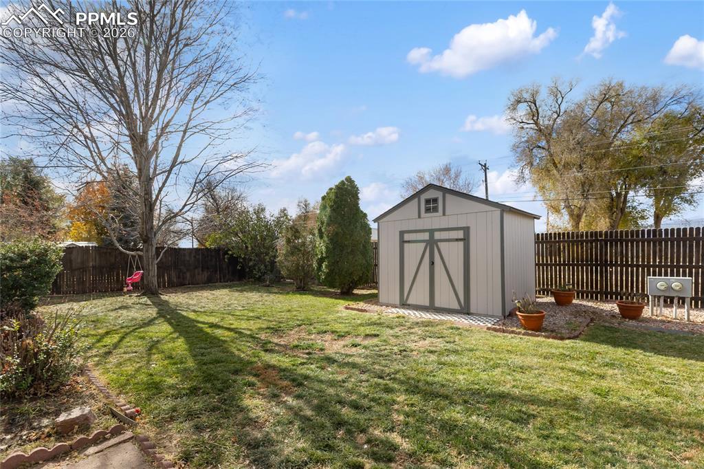 Fenced backyard featuring a storage shed