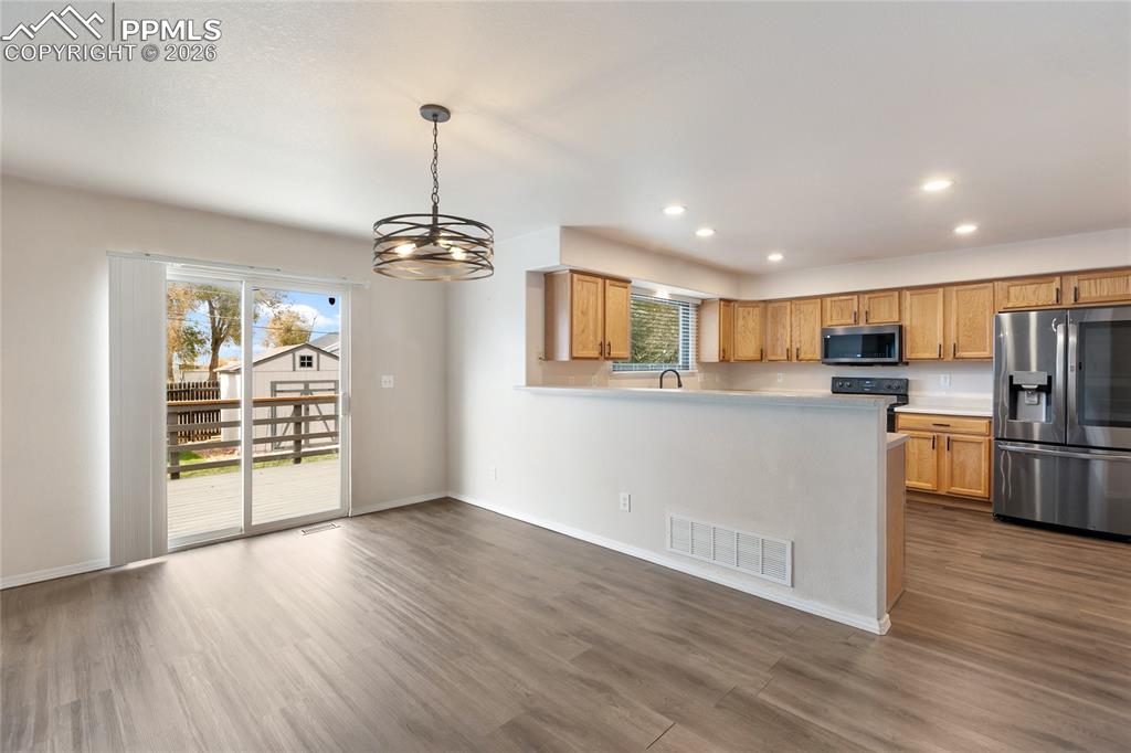 Kitchen with stainless steel appliances, a peninsula, light countertops, hanging light fixtures, and recessed lighting