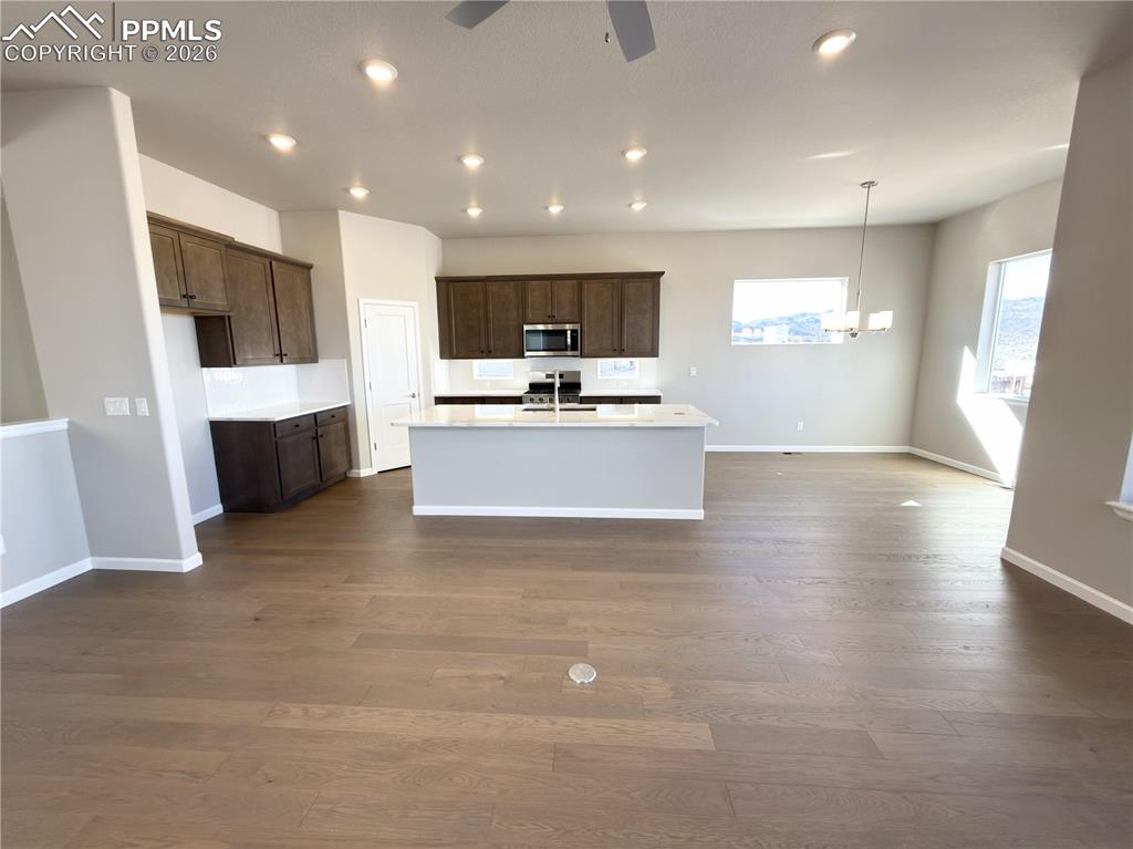 Kitchen with quartz countertops, pantry, large island providing additional seating, stainless steel gas range, microwave, and dishwasher!