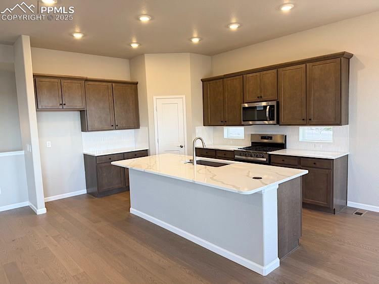 Kitchen with quartz countertops, pantry, large island providing additional seating, stainless steel gas range, microwave, and dishwasher!