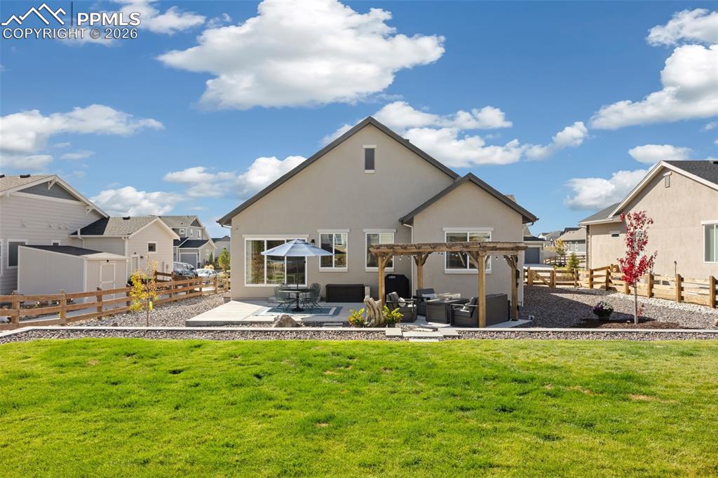 Back of house with spacious patio area, a fenced backyard, stucco siding, and pergola.