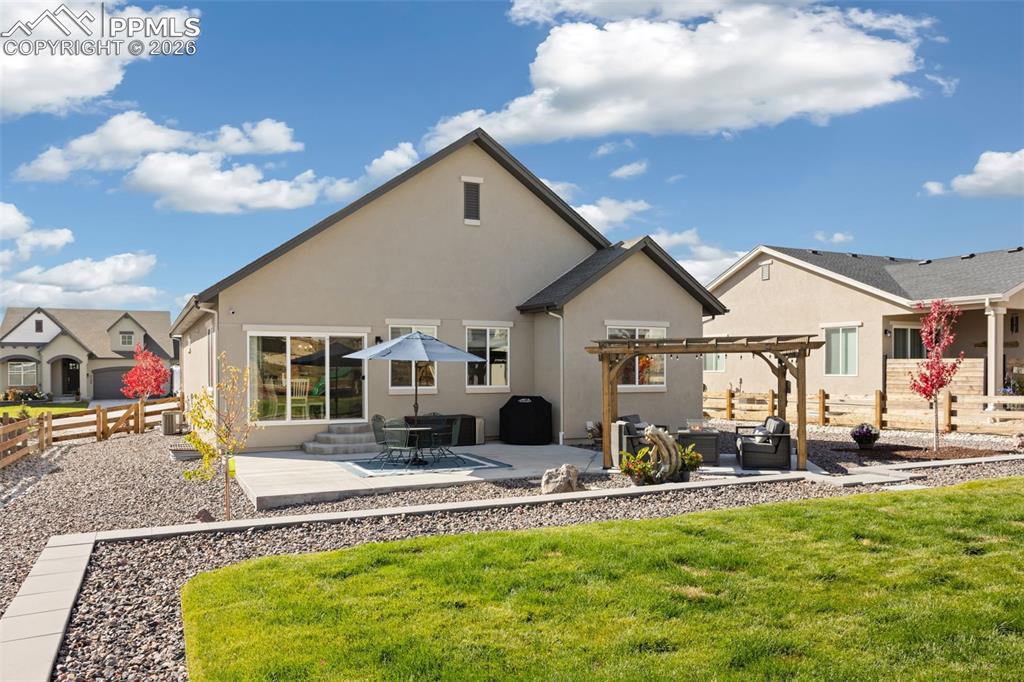 Rear view of house featuring a patio, stucco siding, a pergola, and an outdoor lounge area