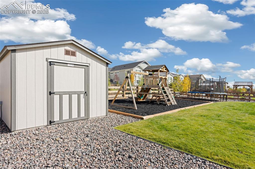 View of 12x10 Tuff Shed with a playground, a trampoline, and a residential view