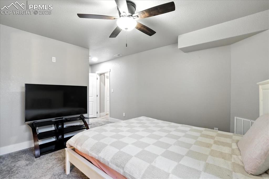 Carpeted bedroom featuring a ceiling fan and a textured ceiling