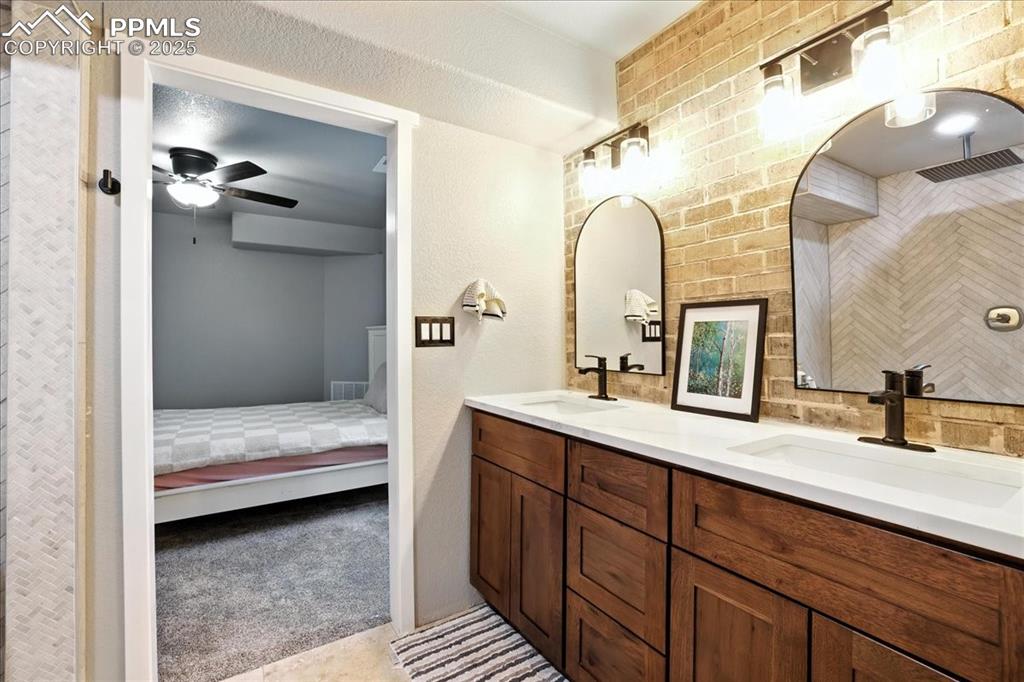 Ensuite bathroom with double vanity, a ceiling fan, and a shower