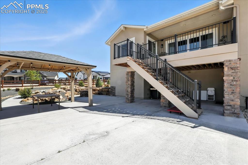 View of patio with stairs and a gazebo