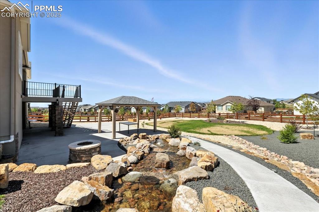 Fenced backyard featuring a residential view, a gazebo, a fire pit, a patio area, and stairway