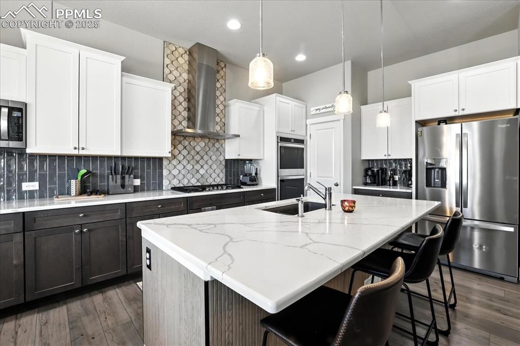 Kitchen featuring stainless steel appliances, decorative backsplash, white cabinets, dark wood finished floors, and recessed lighting