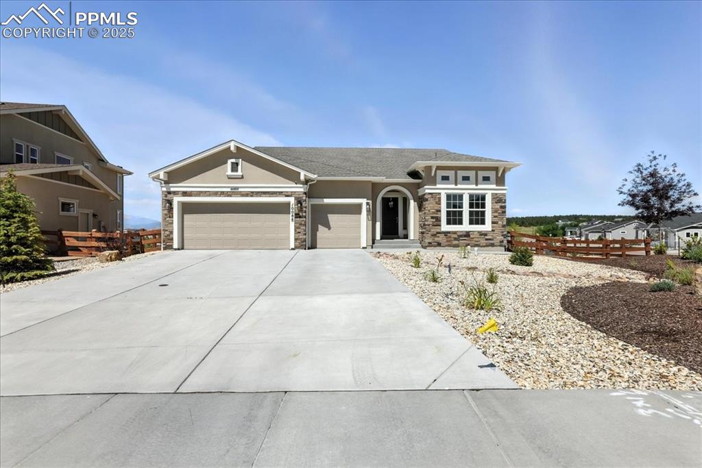 View of front of property featuring stone siding, an attached garage, concrete driveway, and stucco siding