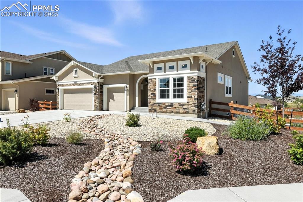 View of front of home featuring stone siding, an attached garage, stucco siding, and concrete driveway