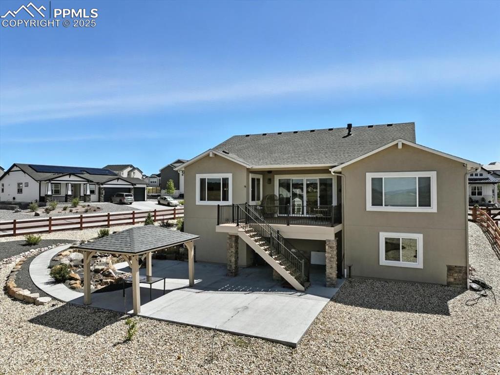 Back of property with a patio, stucco siding, a residential view, and a shingled roof