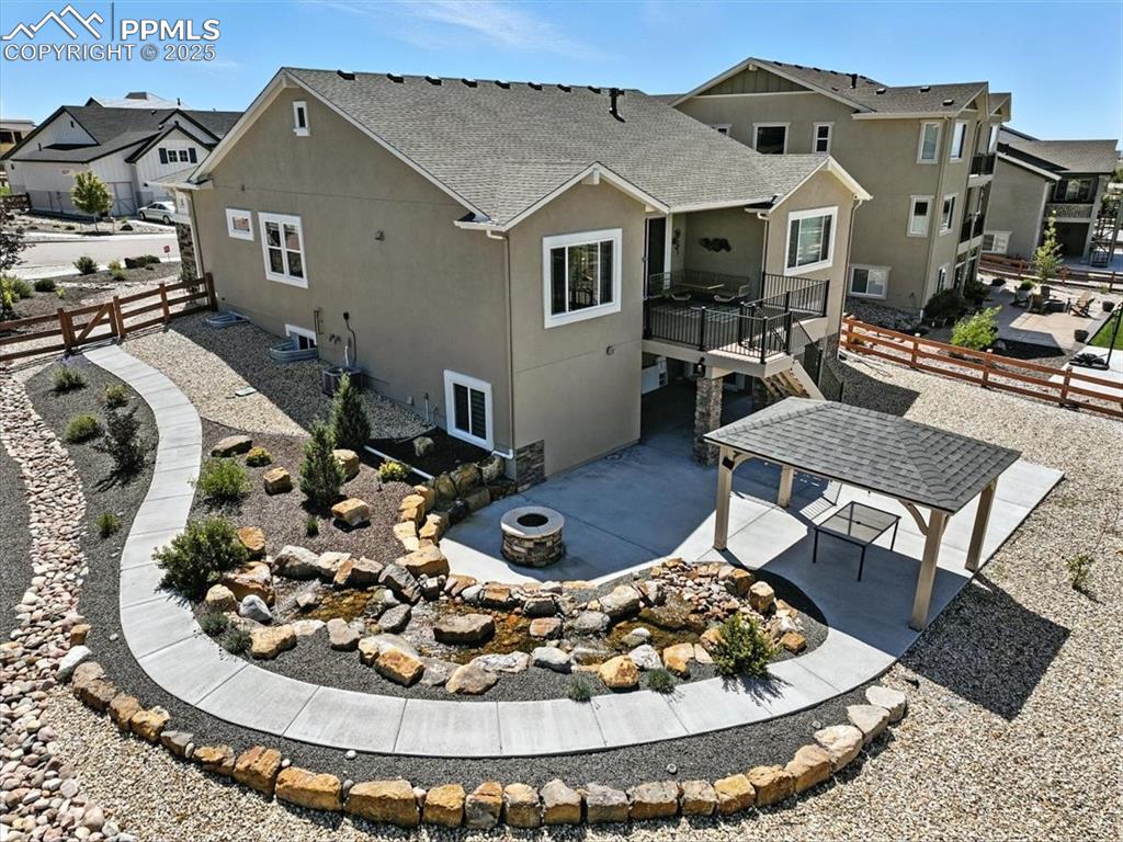 Back of property featuring a fire pit, a residential view, stucco siding, and a patio
