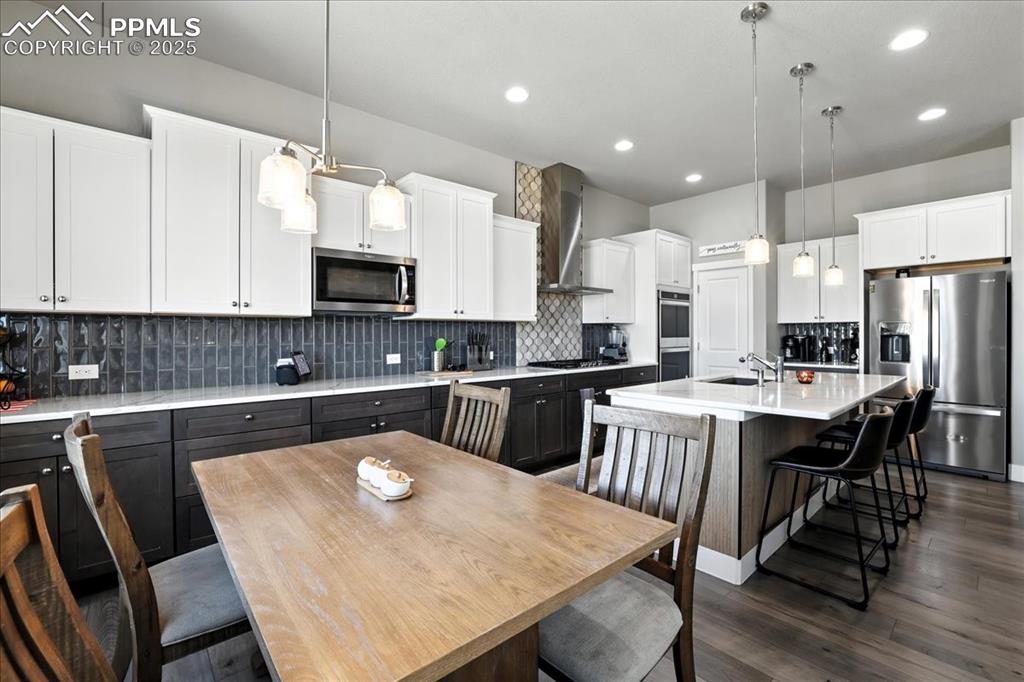 Kitchen with appliances with stainless steel finishes, decorative backsplash, a kitchen bar, white cabinetry, and recessed lighting
