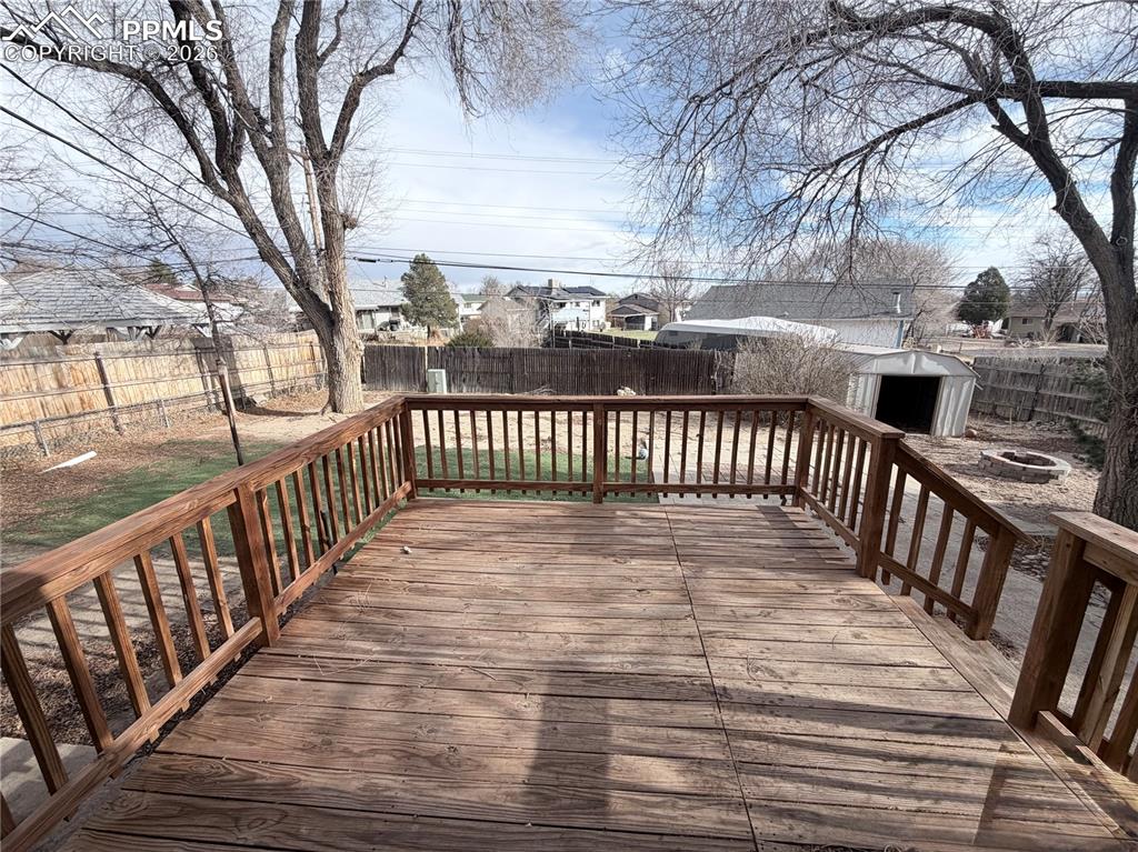 Wooden deck with a fenced backyard, a residential view, an outdoor fire pit, and a shed