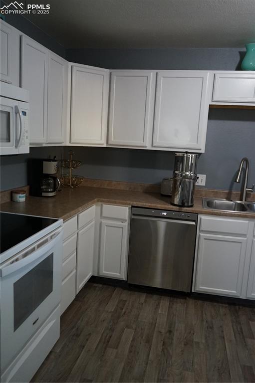 Kitchen with stove, white cabinetry, dishwasher, and dark wood-type flooring