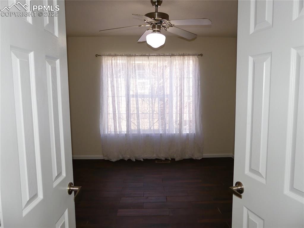 Primary bedroom featuring dark wood-type flooring, baseboards, and ceiling fan