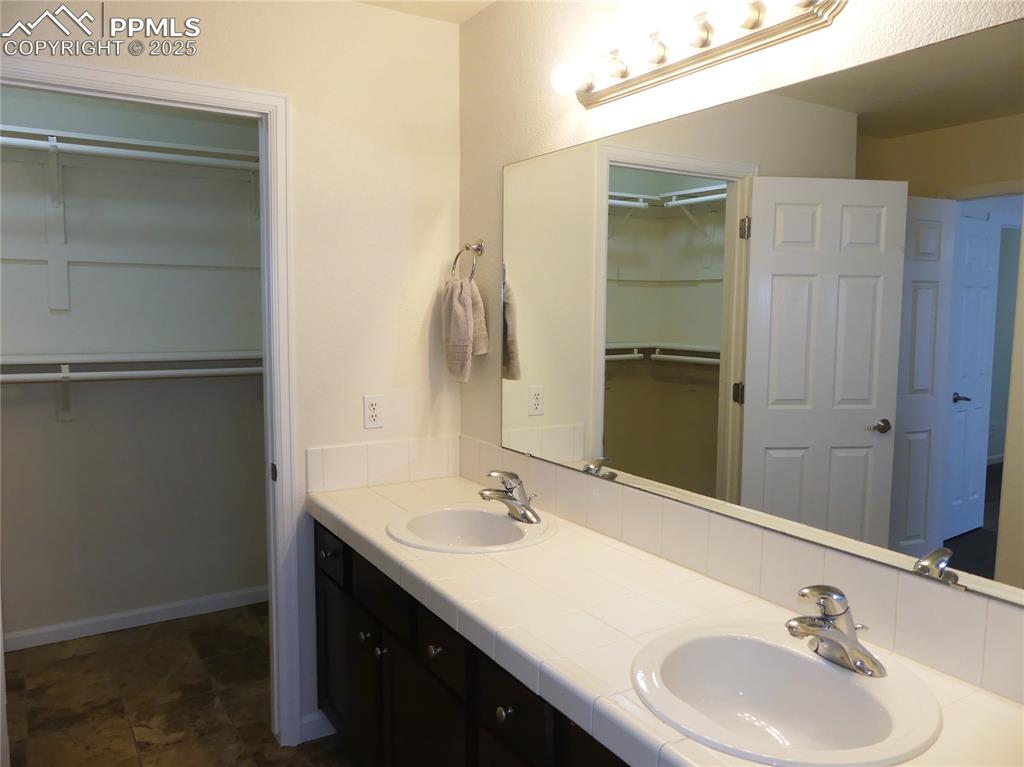 Bathroom featuring double vanity, a sink, and a spacious closet