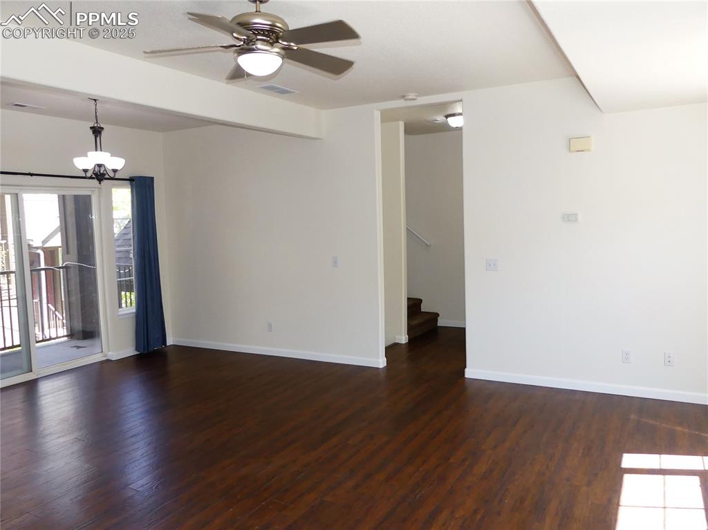 Dining room with baseboards, wood finished floors, stairway, and ceiling fan with notable chandelier