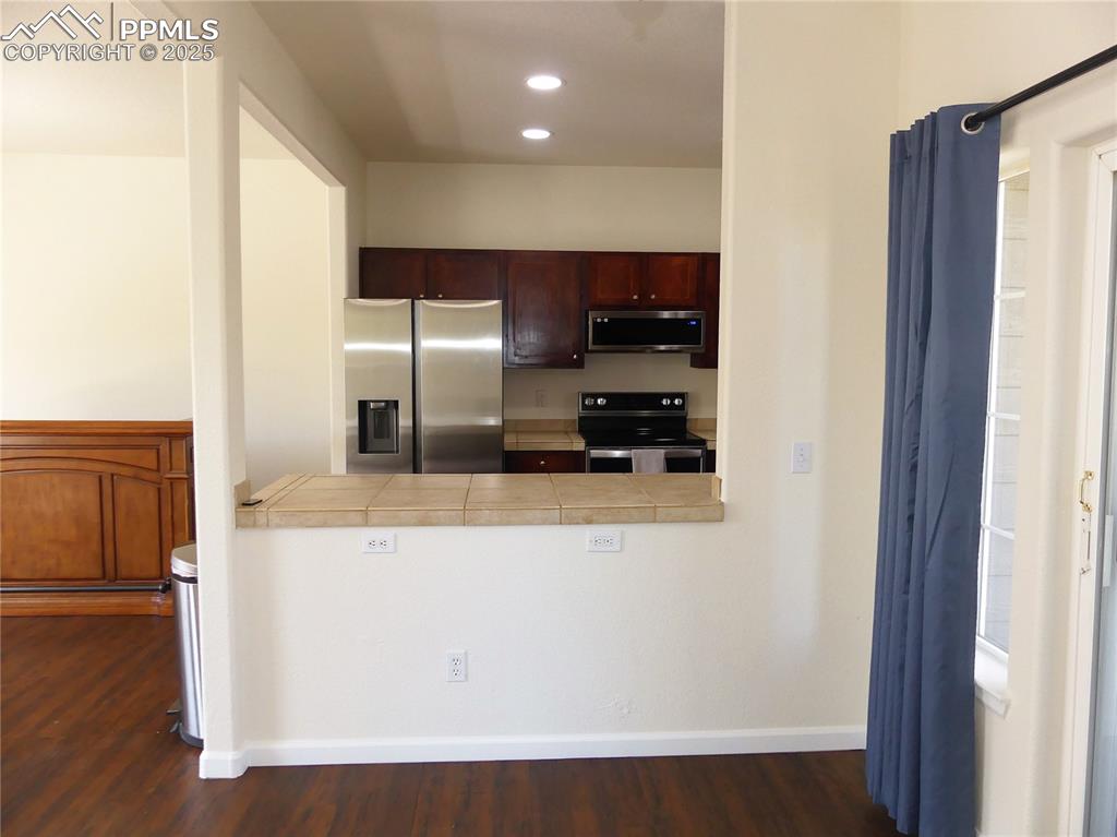 Dining room looking towards the Kitchen featuring appliances with stainless steel finishes, baseboards, a peninsula, dark wood-style floors, and recessed lighting