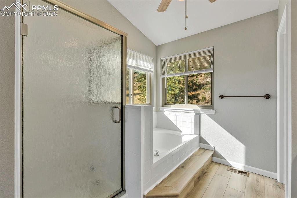 Full bathroom featuring new flooring, a soaking tub, step in shower and private water closet.