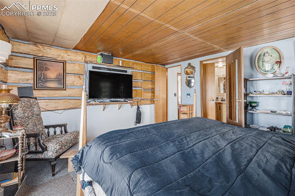 Bedroom with carpet floors, wooden walls, and wooden ceiling