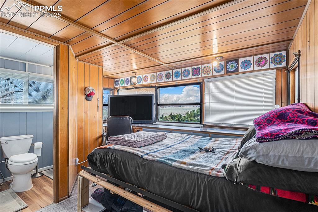 Bedroom with wooden walls, wooden ceiling, and wood finished floors