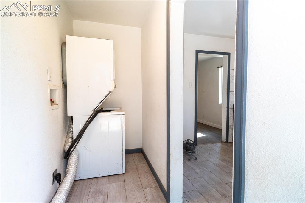 Laundry area with light wood finished floors and stacked washer and clothes dryer