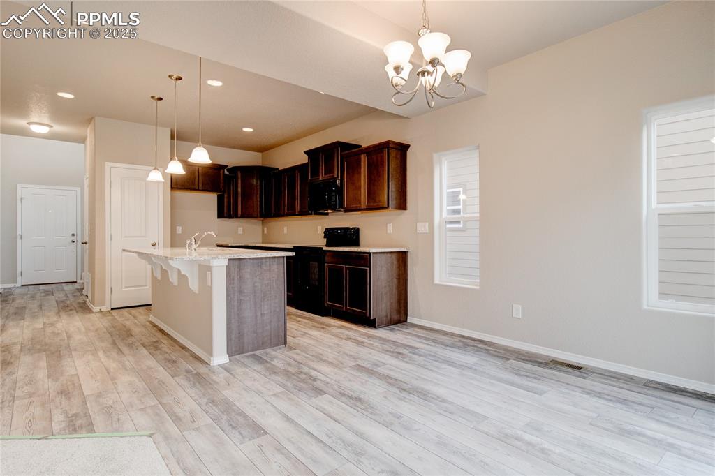 Kitchen featuring a breakfast bar area, hanging light fixtures, black appliances, a chandelier, and recessed lighting