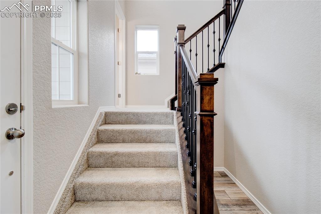 Stairs featuring a textured wall and wood finished floors